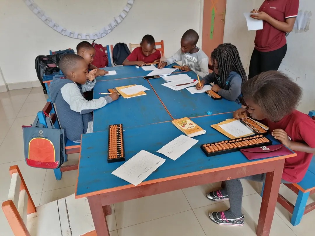 Shenmo Education Rwanda — Small-group training: learners using soroban abacuses under instructor guidance.