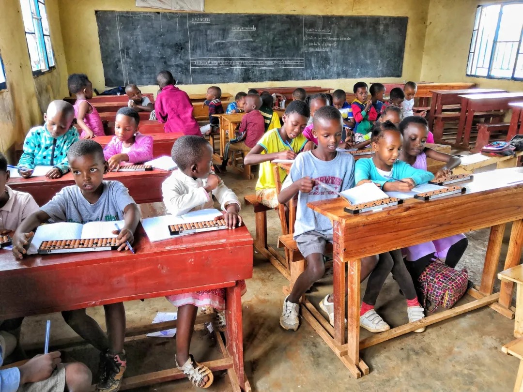 Shenmo Education Rwanda — Full-class practice: students performing abacus work during a bilingual classroom session.