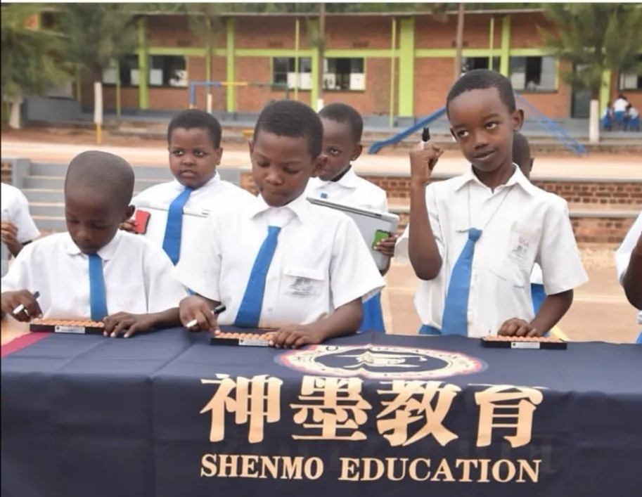 Shenmo Education Rwanda — Outdoor school activity: pupils practicing Abacus Mental Math at a branded Shenmo table.