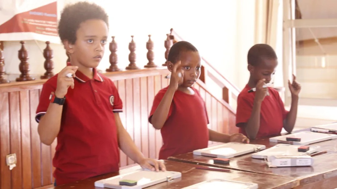 Shenmo Education Rwanda — Mental calculation drill: students responding with whiteboards during timed practice.