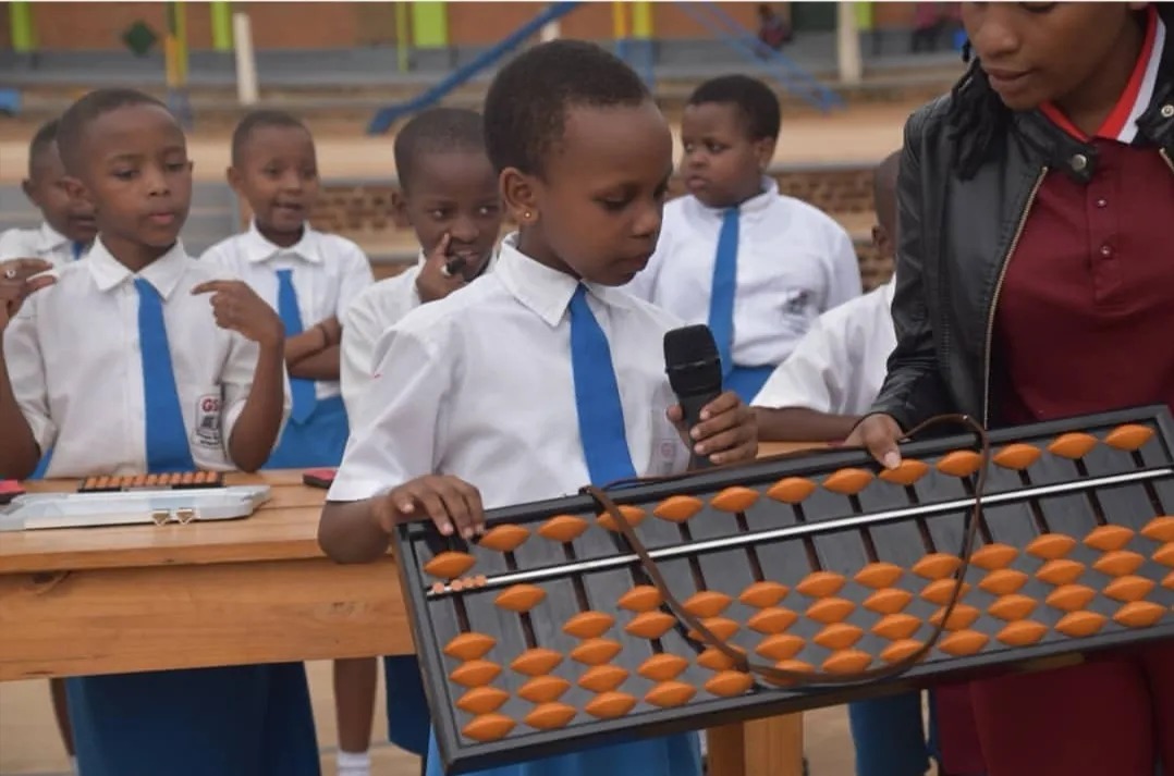 Shenmo Education Rwanda — Teaching demonstration: a student presenting on a large instructional abacus.